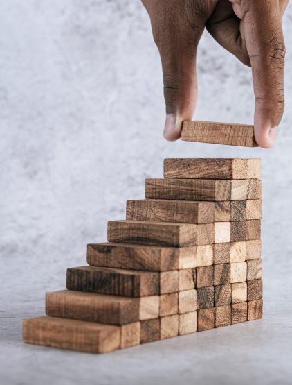 Stacking wooden blocks is at risk in creating business growth ideas.
